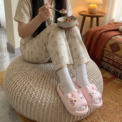 Person sitting on a bean bag chair eating from a bowl, wearing pink slides with cat designs.